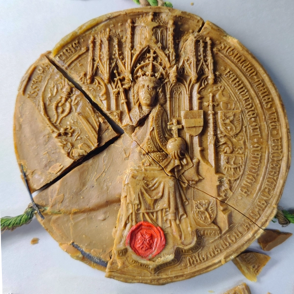 Zerbrochenes Wachssiegel mit dem Abbild eines Königs, vor der Restaurierung, Bildschicht teilweise abgeplatzt.